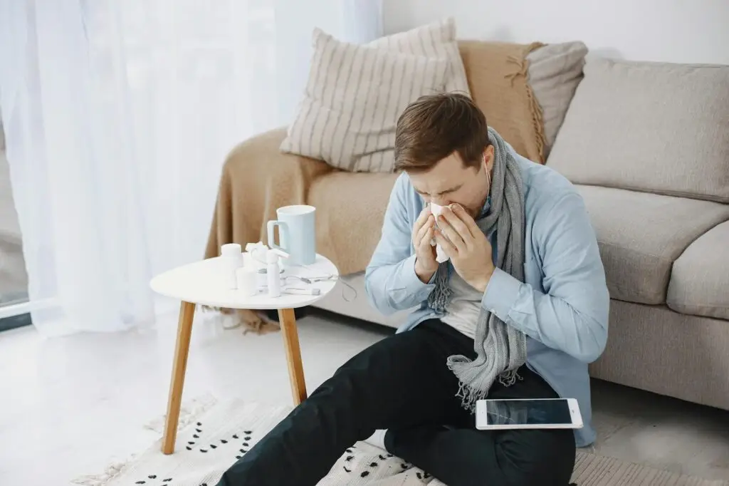 a sick man wiping his nose with tissue