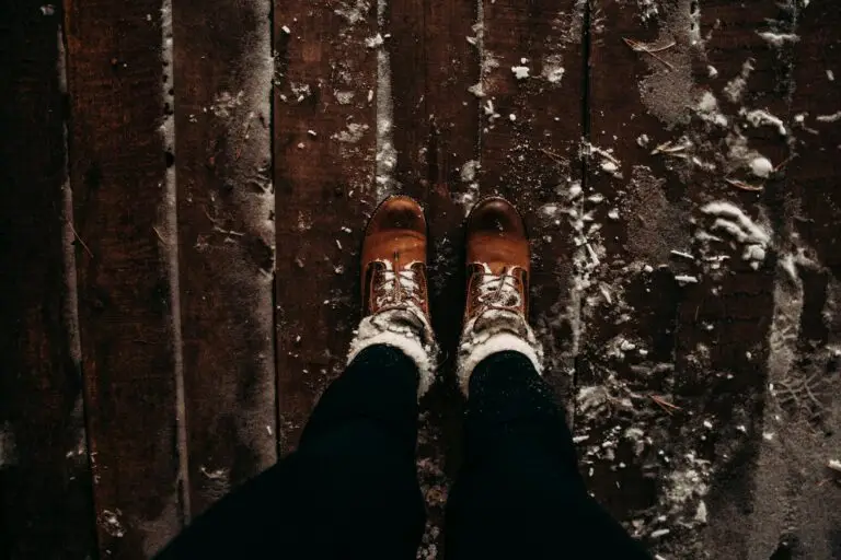 person wearing brown shoes and black pants standing on brown wooden planks