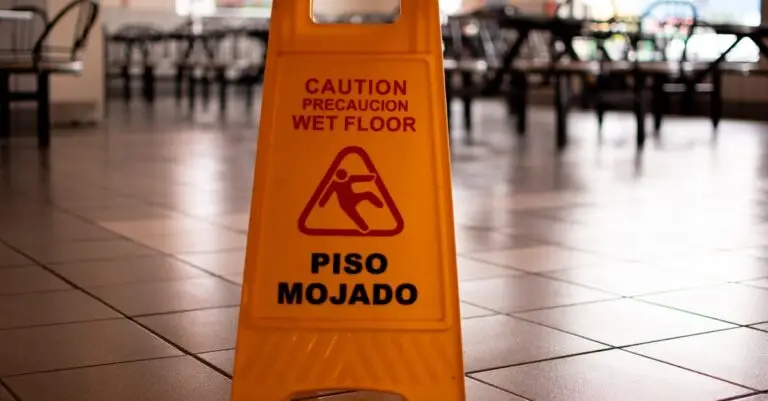 Yellow caution wet floor sign in a cafeteria warns of slippery conditions on tiled floor.
